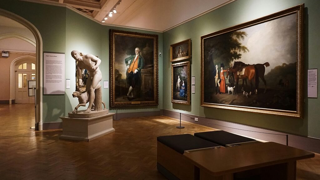 An elegant art gallery room featuring classical paintings and a prominent marble statue.